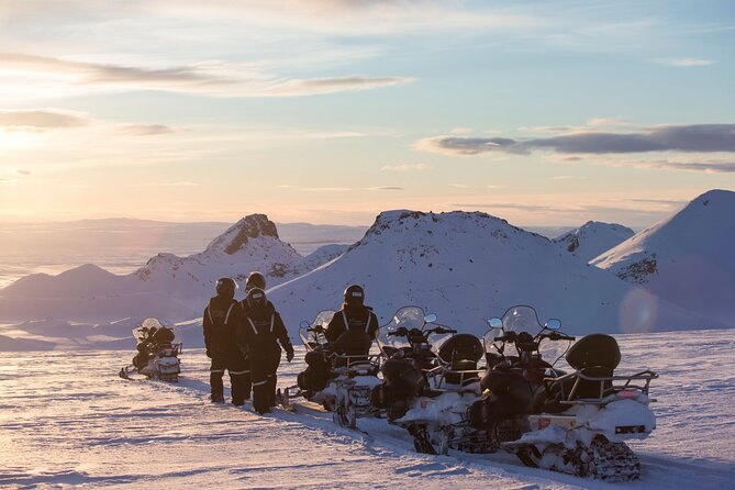 A group of riders stopped out on the ice cap at dusk