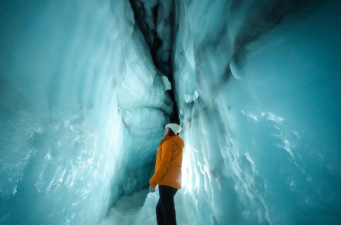 One visitor in a narrow blue chamber inside the glacier ice