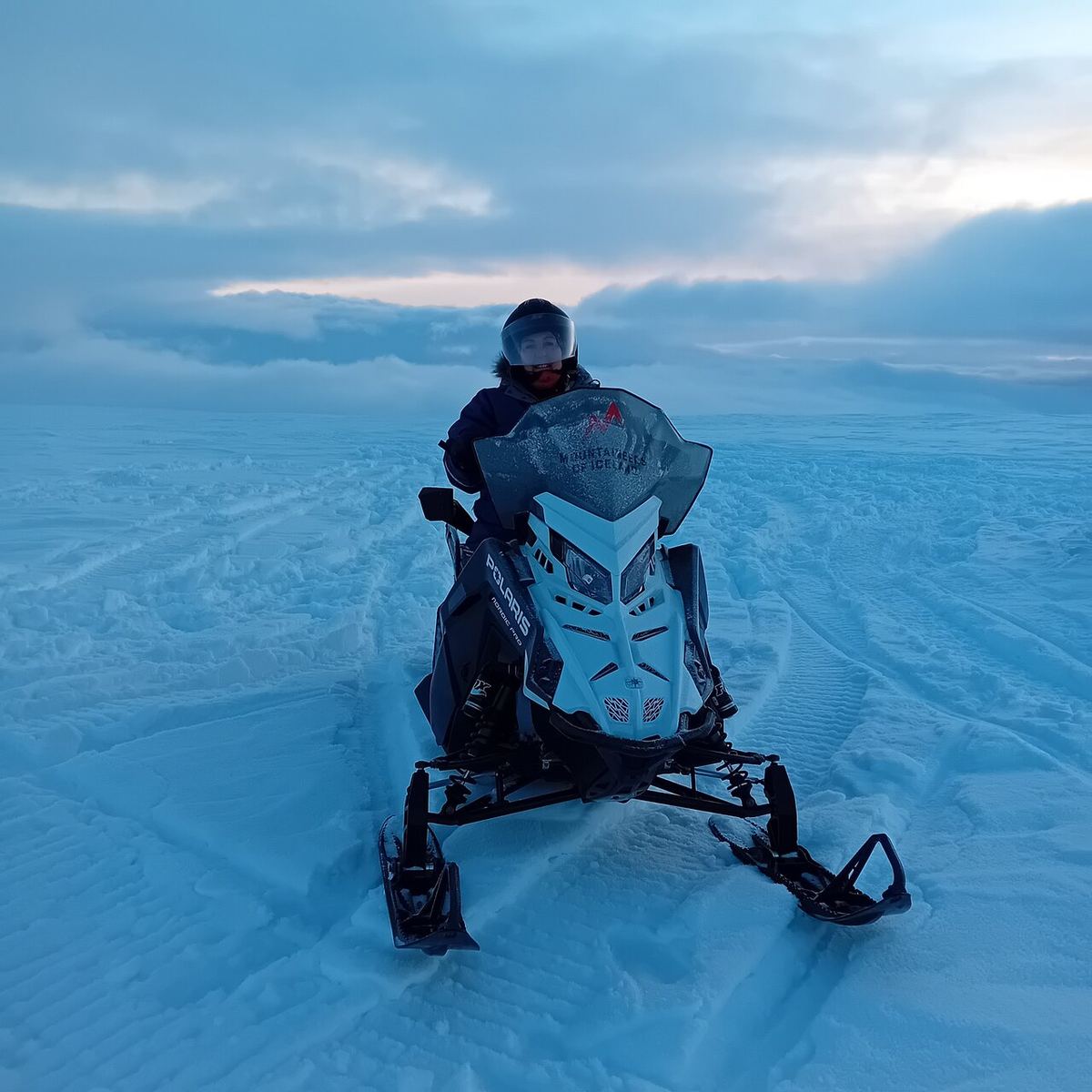 A snowmobile standing on fresh snow under a clear blue sky
