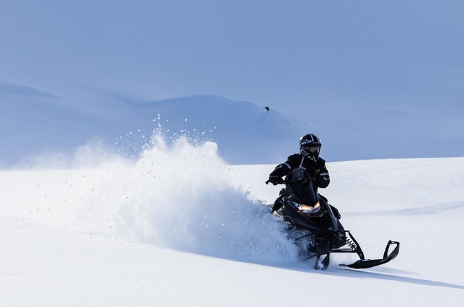 A snowmobile throwing up loose snow on the glacier