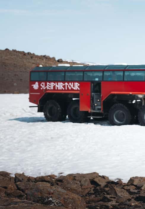 The red Sleipnir monster truck standing on the snow at the edge of the highland road