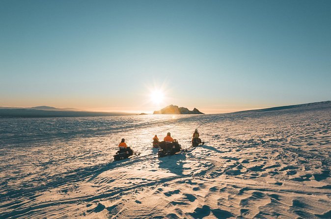 Snowmobiles silhouetted against the sunset on the ice cap
