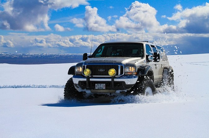 A modified super jeep driving through deep snow on the highland road