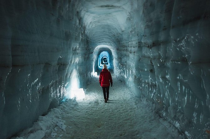 A visitor walking into the lit ice tunnel inside Langjokull